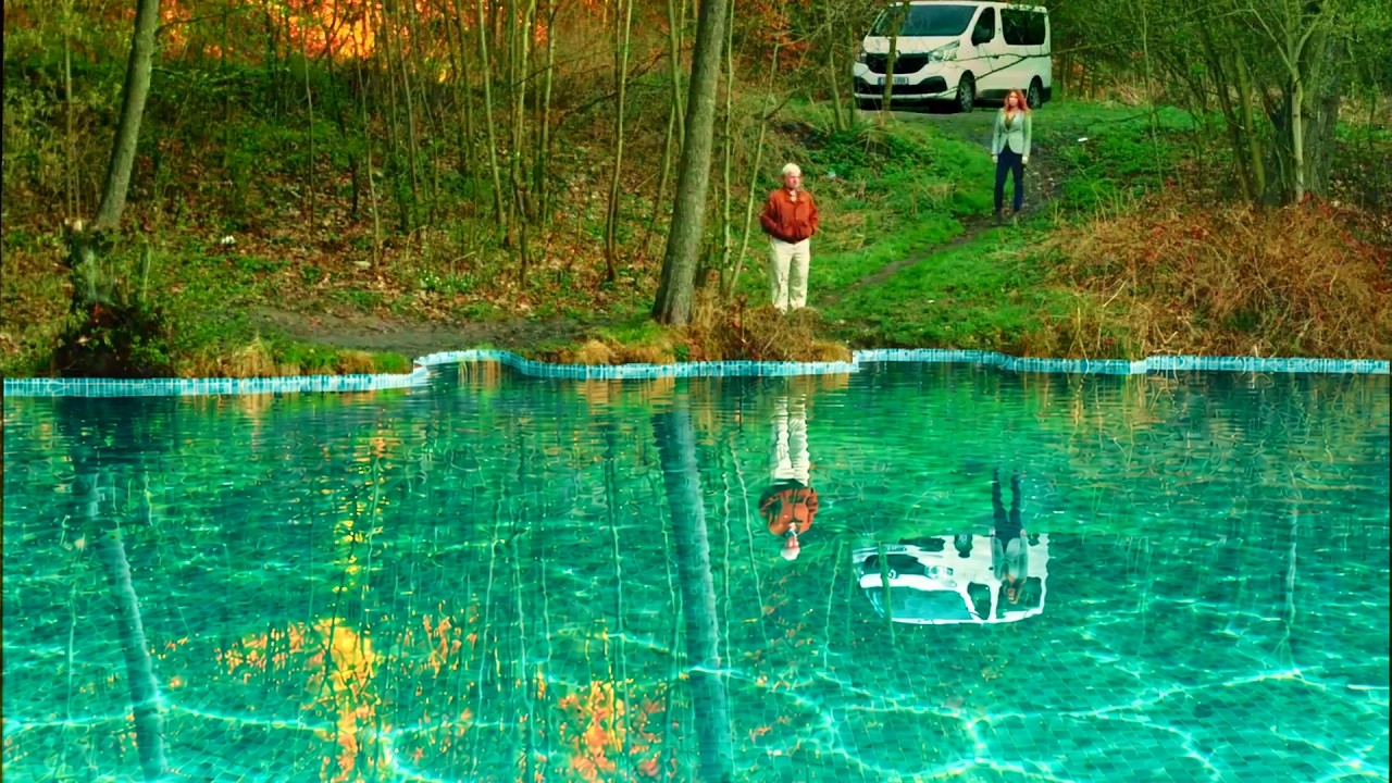 Swimmingpool film still: two people beside a swimming pool in a wooded landscape