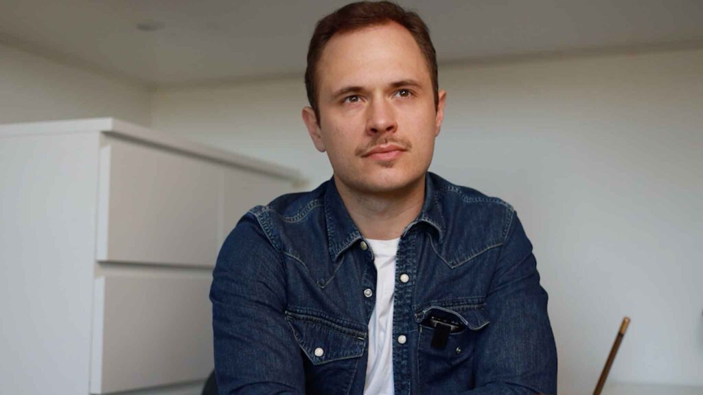 the author sitting by a desk with a pencil in his hand